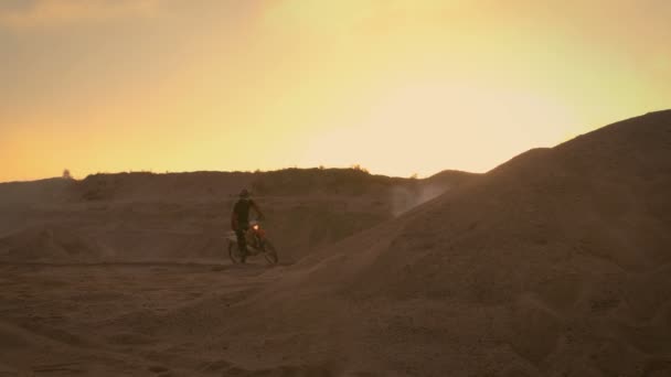 Motocross profesional motociclista conduce a través de la duna y más abajo en la pista todoterreno. Es puesta del sol y la pista está cubierta con humo / niebla . — Vídeos de Stock
