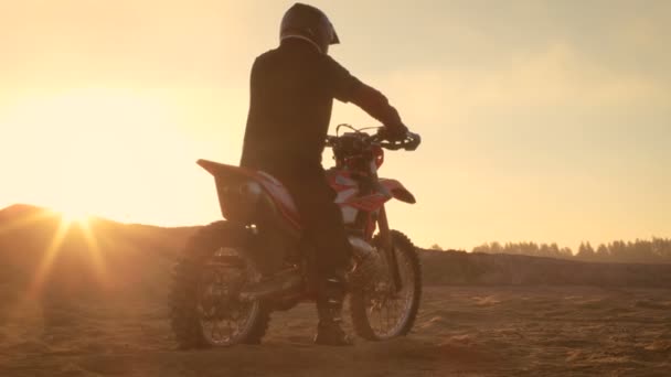 Profesional FMX Motorcycle Rider gira la manija del acelerador completo y comienza a montar en la pista Sandy Off-Road. Puesta de sol escénica . — Vídeos de Stock