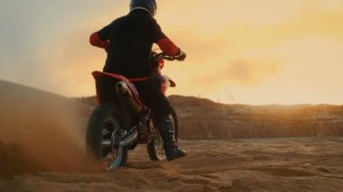 Profesyonel bisiklet binici patlamalar-off onun Fmx motosiklet kumlu Off-Road iz üzerinde. Doğal günbatımı üzerinde arka plan olduğunu.