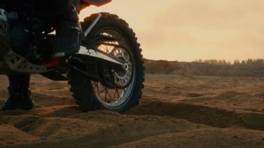 Profesyonel motokros motosiklet binici Off-Road kum arazi üzerinde kullanıyor. Doğal taş ocağı batan güneşin ile atış.
