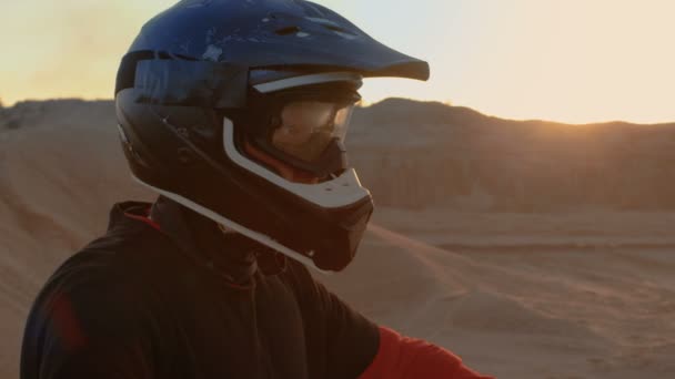 Close-up portret Shot van de Extreme motorcross rijder in een koele beschermende helm permanent op het Off-Road terrein gaat hij te overwinnen. Achtergrond is Sandy Track. — Stockvideo