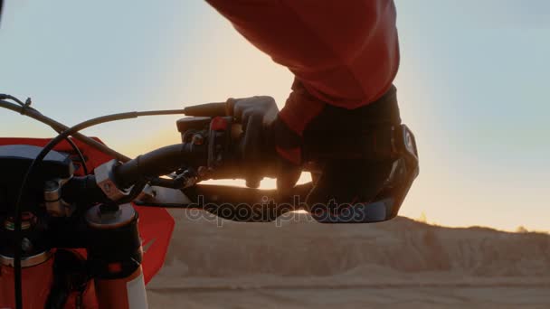 Detail motocyklistu ruky kroucení plynovou rukojeť zároveň stojí na malebném lomu terénu v západu slunce. — Stock video