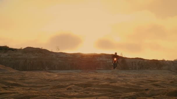 Motocross profesional motociclista conduce a través de la duna y más abajo en la pista todoterreno. Es puesta del sol y la pista está cubierta con humo / niebla . — Vídeos de Stock