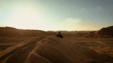 Dune üzerinde sürüş profesyonel motokros motosiklet binici ve Off-Road parça aşağı daha fazla. O gün batımı ve parça dumanla kaplı / sis.