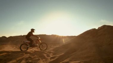 Yan görünümü görüntüleri Dune üzerinde sürüş profesyonel motokros motosiklet binici ve daha aşağı Off-Road parça. O gün batımı ve parça dumanla kaplı / sis.