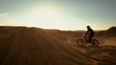 Profesyonel motokros motosiklet binici Dune atlama ve Off-Road parça aşağı daha fazla. Güneş batıyor görürken ocağı terk vurdu.