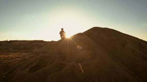 Rider profesjonalne Motocross Fmx motocykl dyski na piaszczystych wydmach i zatrzymuje się tam, aby Goście mogą podziwiać malowniczy zachód słońca. — Wideo stockowe
