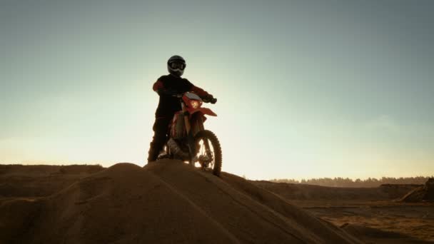 Motocross Rider professionista su FMX Motorcycle Stand sulla sabbia Dune e si affaccia su tutto il terreno estremo fuoristrada che ha intenzione di cavalcare oggi . — Video Stock