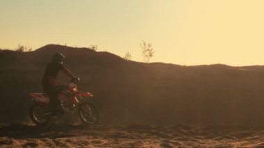 Yan görünümü Shot profesyonel motokros motosiklet binici Dune ve durur sürücüleri. O gün batımı ve parça dumanla kaplı / sis.