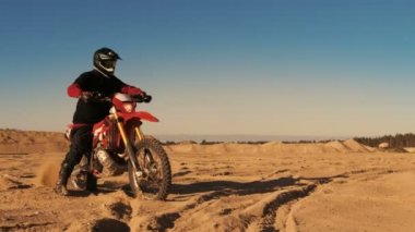 Fmx motosiklet binici tam gaz kolu katlanmış ve Sandy Off-Road yolda sürme başlar. Doğal günbatımı.