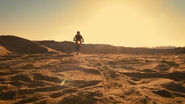 Colpo lungo del pilota professionista Bike Blasts-off sulla sua moto FMX su Sandy Off-Road Track. Scenic Quarry con un tramonto è sullo sfondo . — Video Stock