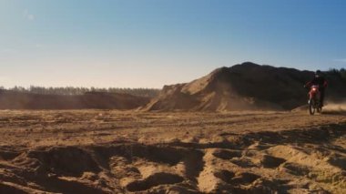 Yan görünümü görüntüleri Dune üzerinde sürüş profesyonel motokros motosiklet binici ve daha aşağı Off-Road parça. O gün batımı ve parça dumanla kaplı / toz / kir.