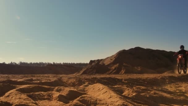 Filmato della vista laterale del motociclista professionista Motocross che guida sulla Duna e più avanti lungo la pista fuoristrada. E 'tramonto e pista è coperto di fumo / nebbia . — Video Stock