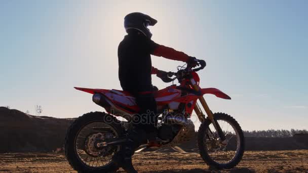 Kant weergave beelden van de motorrijder van de professionele motorcross rijden op het duin en verder naar beneden de Off-Road Track. Het is de zonsondergang en Track is bedekt met rook / stof / vuil. — Stockvideo