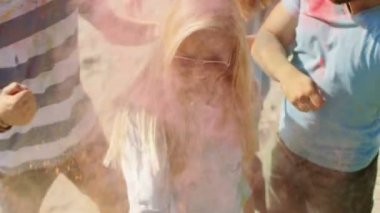 Kalabalığın ortasında Hindu Holi Festivali kutlamaları renkli toz atarak sarışın kız yüksek açı çekim. Bu güneşli günde büyük eğleniyorlar.