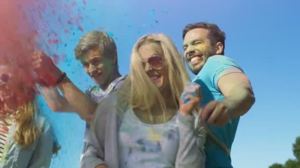 Багатоетнічних група молодих людей кинути барвисті порошку один на одного в святкування холі фестивалю. Вони мають величезне задоволення на цьому сонячний день. — стокове відео