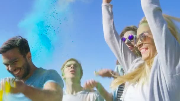 Grupa wieloetnicznego zróżnicowanych zróżnicowany młodych ludzi skakać i rzucać kolorowy proszek w powietrzu z okazji festiwalu Holi. Mają one ogromne zabawy w ten słoneczny dzień. — Wideo stockowe
