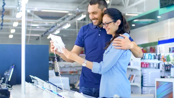 En la tienda de electrónica Hermosa pareja joven mira en las últimas — Foto de Stock