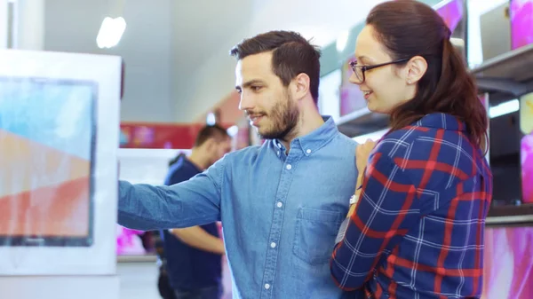 Beau jeune couple dans le magasin d'électronique Navigation sur, Lookin — Photo