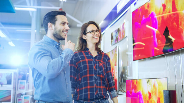 Молодая пара покупки для нового 4K телевизор в электронике Sto
