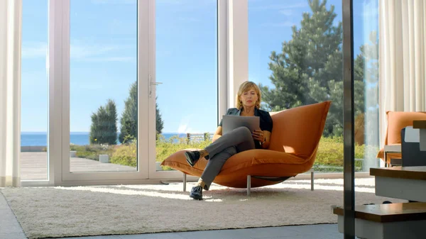 Güneşli onu kanepede otururken kadın kıdemli kullanır Laptop 