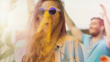 Güzel sarışın kız dansları kutlama Holi Festivali'nin arkadaşları ile yakın çekim portre. Onu yüz ve kıyafet renkli toz ile kaplıdır. İnsanlar arka planda dans.