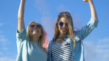 İki güzel sırt kız gülmek ve onlar uçan Holi Festivali renkli toz kutlamak mutlu. Vakit var. Clear Sky ve Blue Sea içinde belgili tanımlık geçmiş.
