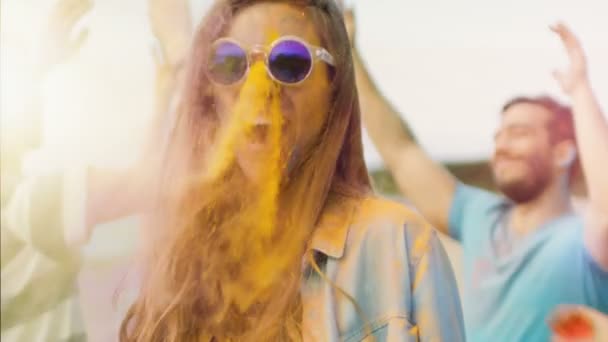 Close-up Portrait of a Beautiful Blonde Girl Dances in Celebration of Holi Festival With Her Friends. Her Face and Clothes are Covered with Colorful Powder. People Dancing in the Background. — Stock Video