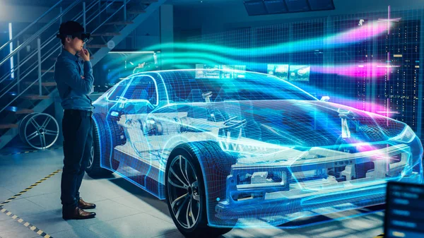 Engineer Wearing Augmented Reality Headset Working on New Electric Car Chassis Platform. 3D Graphics Visualization Virtual Model of a Vehicle is Tested in Digital Wind Tunnel. — Stock Photo, Image