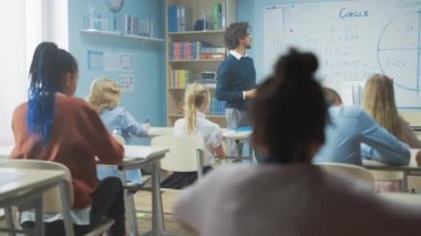 Bakım Öğretmeni Parlak Çeşitli Çocuklarla dolu bir sınıfa Dersi Açıklıyor. Çok Irklı Çocuklar Öğrenme Bilimi Grubu ile İlköğretim Okulu 'nda. Yavaş Hareket eden Kamera