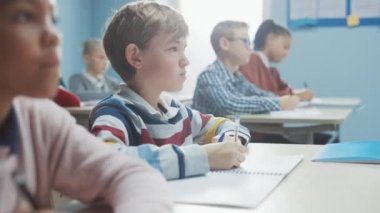 İlköğretim Okulu Sınıfı: Zeki Beyaz Çocuğun Portresi Egzersiz Defteri Yazıyor, Sınav ve Yazma Sınavı. Çeşitli Parlak Çocuklar Grubu Özenle Çalışıyor ve Öğreniyor