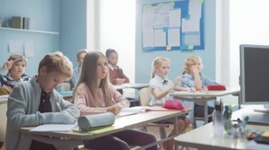 İlköğretim Sınıfı Çocuklar Öğretmenlerinin Ders Vermesini Dikkatle Dinliyor. Doğru cevabı bilen herkes elini kaldırsın. Okuldaki Genç Çocuklar Bilim Öğreniyor ve Yaratıcı Düşünüyor
