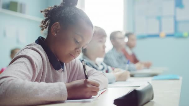 In Elementary School Class: Portrait of Brilliant Girl with Braces Writes in Exercise Notebook, Smiles. Junior Classroom with Diverse Group of Bright Children Working Diligently and Learning New Stuff — Stock Video