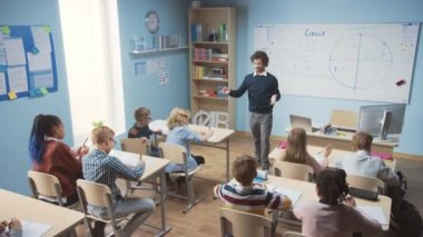 Coşkulu Öğretmen Çok Irklı Çocuklar İlköğretim Okulu Öğrenme Bilimi ve Yaratıcı Düşünme Grubu 'nda çeşitli parlak çocuklarla dolu bir sınıfa ders veriyor. Yükseltilmiş Kamera Görüntüsü