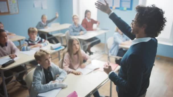 Základní učebna různorodých bystrých dětí poslouchá učitele, který dává lekci. Každý zvedne ruku, když zná správnou odpověď. Brilantní děti ve školním vzdělávání. Učitel přes rameno výstřel — Stock video