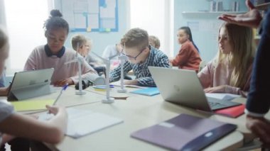 İlköğretim Okulu 'nda: Zeki Genç Çocuklar Sınıfı Rüzgar Türbinlerini Programlamak için Tablet Bilgisayarları Kullanarak Takım Çalışır. Yenilenebilir Enerjinin Çevre dostu formlarını öğrenen çocuklarla dolu sınıf