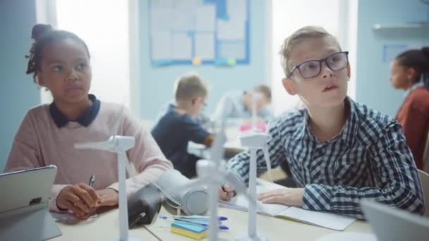 In der Grundschule: Klasse brillanter Kleinkinder arbeitet im Team mit Tablet-Computern, um Windräder zu programmieren. Unterricht mit Kindern über umweltfreundliche Formen erneuerbarer Energien — Stockvideo