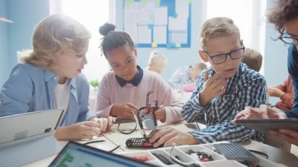 Elementary School Robotics Classroom: Vielfältige Gruppe brillanter Kinder mit begeisterten Lehrern, die Roboter bauen und programmieren. Kinder lernen Software-Design und kreative Robotik — Stockvideo