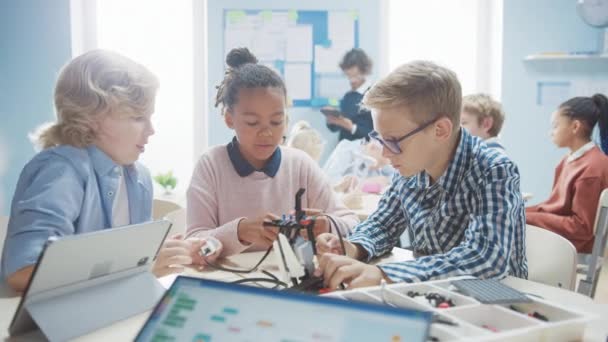 Elementary School Robotics Classroom: Diverse Group of Brilliant Children with Enthusiastic Teacher Building and Programming Robot (en inglés). Diseño de software de aprendizaje para niños e ingeniería de robótica creativa — Vídeo de stock