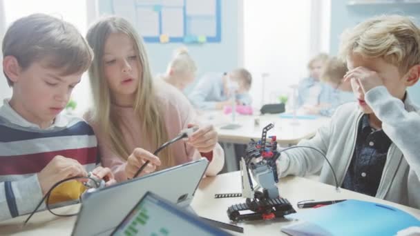 Elementary School Robotics Classroom: Diverse Gruppe brillanter Kinder, die Roboter bauen und programmieren, reden und als Team arbeiten. Kinder lernen Softwaredesign und kreative Robotertechnik — Stockvideo