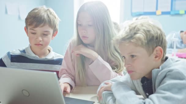 小学校教室:ソフトウェアプログラミング、会話、チームとして働くためにラップトップコンピュータを使用して鮮やかな子供たちの多様なグループ。子供たちはソフトウェアの設計と創造的な思考を学ぶ — ストック動画