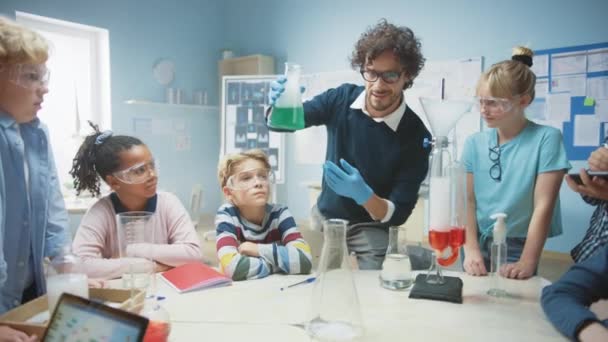 Класс химии и естественных наук начальной школы: Энтузиастичный учитель показывает забавный эксперимент химической реакции для группы детей. Смешивание химических веществ в стакане, чтобы они стреляли пены (слоновой зубной пасты ) — стоковое видео