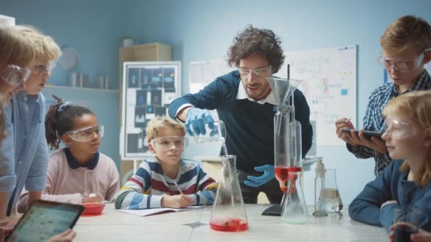 Scuola Elementare Chimica Aula: Insegnante Entusiasta Insegna Diverso gruppo di bambini mostra Science Reaction Experiment mescolando sostanze chimiche in Beaker in modo da sparare schiuma (dentifricio elefante ) — Video Stock