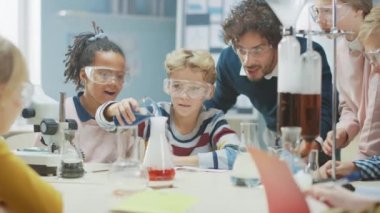 İlköğretim Okulu Bilim Sınıfı: Coşkulu Öğretmen Kimyayı Çeşitli Çocuklar Grubu 'na Açıkladı, Küçük Çocuk Kimyasalları Beakers' a Karıştırdı. Çocuklar Faiziyle Öğrenin