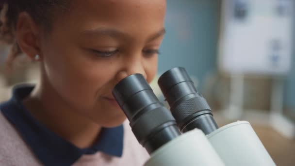 Retrato de una colegiala inteligente mirando bajo el microscopio. En el aula de la escuela primaria linda chica utiliza microscopio. Programa de Educación STEM (ciencia, tecnología, ingeniería y matemáticas) — Vídeo de stock