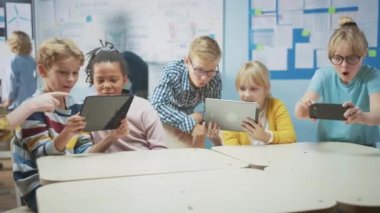 Okul Bilgisayar Bilimi Sınıfı: Öğrenciler Artırılmış Gerçeklik Yazılımı ile Dijital Tablet Bilgisayarlar ve Akıllı Telefonlar Kullanıyorlar, Heyecanlılar, Harikalar Dolu. STEM 'deki Çocuklar, Oynuyor ve Öğreniyor