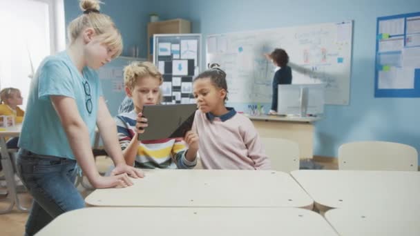 Elementary School Computer Science Class: Two Girls and Boy Use Digital Tablet Computer with Augmented Reality Software, Theyre Excited, Full of Wonder, Curiosity. Niños en STEM, Jugar, Aprender — Vídeos de Stock