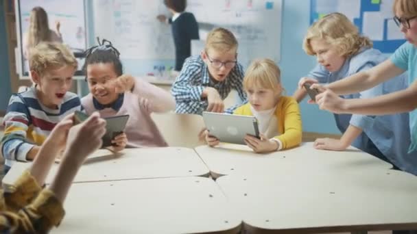 Informatikunterricht in der Grundschule: Kinder benutzen digitale Tablet-Computer und Smartphones mit Augmented-Reality-Software, sie sind aufgeregt, voller Wunder. Kinder in MINT, Spielen und Lernen — Stockvideo