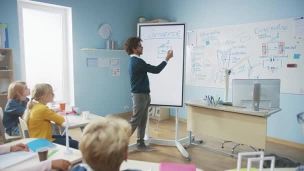 Le professeur de physique de l'école primaire utilise un tableau blanc numérique interactif pour montrer à une salle de classe remplie d'enfants intelligents et diversifiés comment fonctionne le générateur. Classe de sciences avec des enfants curieux écoutant attentivement — Video