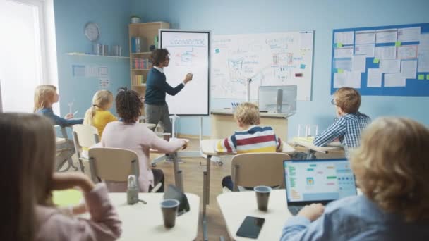 Elementär skolfysik Lärare använder interaktiv digital whiteboard för att visa ett klassrum fullt av smarta diverse barn hur Generator fungerar. Science Class med nyfikna barn lyssnar uppmärksamt — Stockvideo